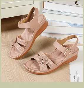 Detailed view of women's pink wedge sandals featuring floral accents and laser-cut patterns