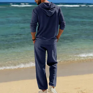 Rückansicht eines atmungsaktiven blauen Herren-Leinen-Sets mit Hoodie am Strand
