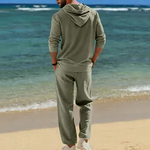 Grünes Herren Leinen-Set mit Kapuzenpullover und Hose, Rückansicht am Strand.