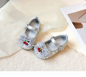 Close-up detail of silver glitter girls princess shoes with cherry and tulle bow-knot