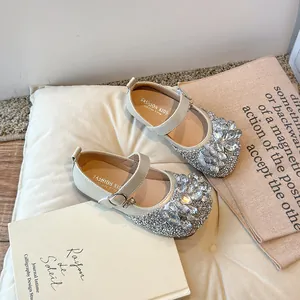 Chaussures Mary Jane élégantes pour filles avec décoration en strass sur un coussin beige.