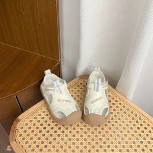 Vue détaillée de sandales crème pour enfants avec semelles souples sur chaise.