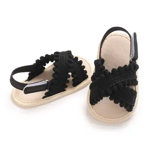 Vista detallada de sandalias negras para bebé niña con pompones y suela blanda flexible