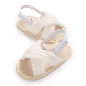 Vista detallada de sandalias blancas para bebé con lindos pompones y velcro