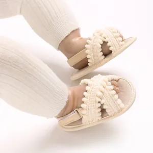 Detalle de sandalias transpirables para bebé con ribete de pompones y suela suave