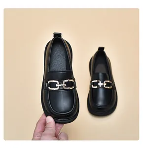 Nahaufnahme von schwarzen Kinder-Leder-Loafers mit stilvoller goldener Kette