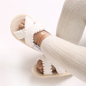 Detalle de sandalias blancas para bebé con correas cruzadas y bordes de volantes