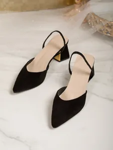 Detail view of French style black suede pointed-toe slingback pumps with gold heels