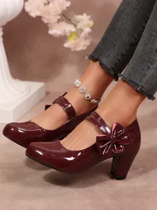 Primo piano di eleganti décolleté in vernice bordeaux con tacco a blocchi e fiocco