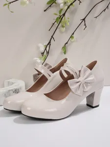 Dettaglio di eleganti scarpe Mary Jane beige in vernice con tacco largo e fiocco