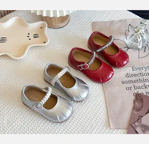 Close-up of red and silver French style Mary Jane shoes for little girls on table