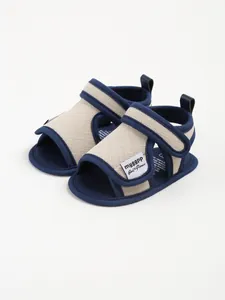 Detailed close-up of breathable canvas baby sandals with navy blue trim and velcro straps