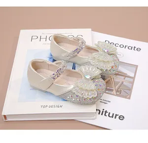 Primer plano de zapatos con lazo de diamantes para niñas con un elegante acabado crema.