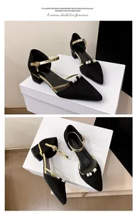 Detail view of black pointed-toe mid-heel sandals with gold buckle straps and pearl decor