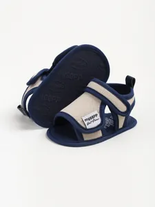 Detailed view of dark blue and beige cotton baby sandals with secure velcro straps.
