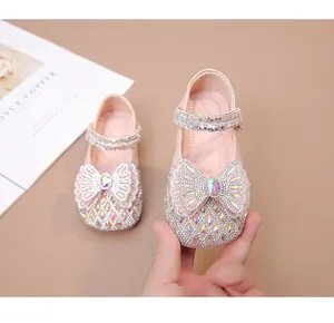 Primer plano de zapatos de princesa rosas para niña con cristales y un gran lazo