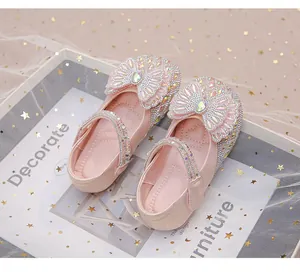 Primer plano de zapatos de princesa rosas para niñas con pedrería brillante y lazos grandes.