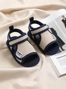 Detailed shot of navy and beige toddler sandals with adjustable straps on silk.
