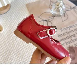 Detail view of red girl's Mary Jane shoe with silver buckle and black gemstone strap