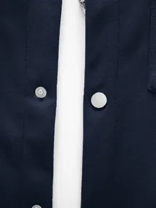 Gros plan sur les boutons-pression en métal argenté et la texture tricotée d'une veste bleu marine