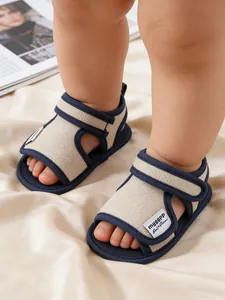 Close-up of soft cotton baby walking sandals with navy blue trim on silk background.