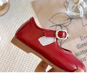 Detailed macro shot of red glossy girls Mary Jane shoe with buckle and white fabric accents