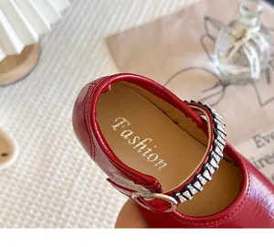 Macro view showing the rhinestone strap and interior of red leather Mary Jane shoes for girls