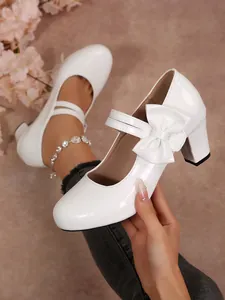Eleganti scarpe bianche con tacco largo, punta tonda, fiocco decorativo e cinturino alla caviglia.
