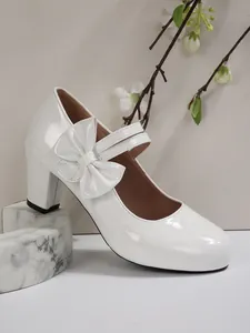 Vista dettagliata di eleganti scarpe Mary Jane in vernice bianca con tacchi e fiocchi