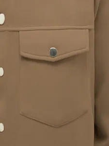 Détail de la poche à rabat avec bouton pression sur une veste décontractée marron