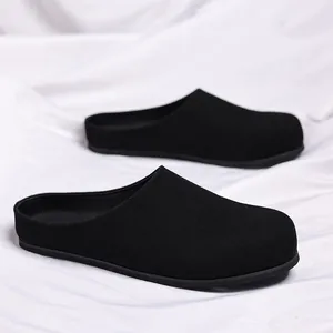 Detailweergave van zwarte matte instappantoffels op een zachte witte stoffen achtergrond