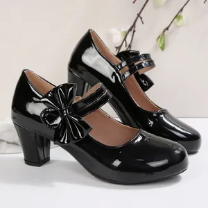 Eleganti scarpe Mary Jane in vernice nera con punta tonda, tacco largo e fiocco alla moda.
