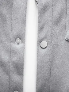 Gros plan sur les boutons-pression argentés et le tissu texturé d'une veste grise pour homme