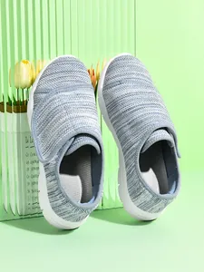 Dettaglio di sneaker in rete traspirante azzurra con cinturini in velcro su sfondo verde