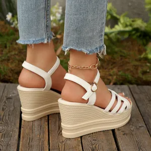 Primo piano di sandali platform bianchi con zeppa e suola con trama intrecciata.