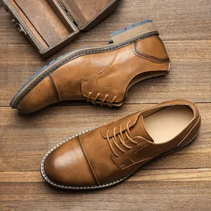 Close-up of vintage brown leather cap-toe derby shoes on a rustic wooden background.