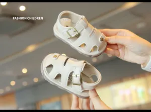 Close-up of cream hollowed-out baby summer sandals with soft soles