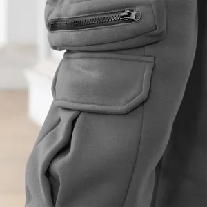 Detailed macro shot of functional zip and flap pockets on grey men's cargo pants