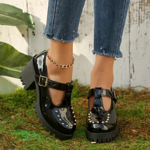 Detail van zwarte lakleren Mary Janes met blokhak en versiering van metalen studs