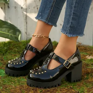 Detailopname van zwarte lakschoenen Mary Jane plateau met gouden studs en T-bandje.