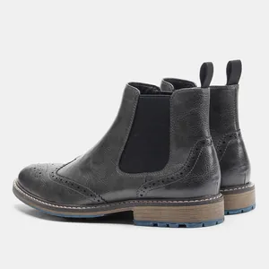 Seitenansicht von schwarzen Chelsea-Boots aus Leder mit Budapester-Muster und blauer Sohle