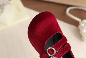 Detailaufnahme eines roten Samtschuhs für Mädchen mit funkelnder Strassschnalle