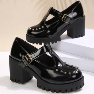 Detailweergave van zwarte laklederen Mary Jane plateauschoenen met gouden studs en T-bandje.