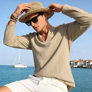 Close-up of a men's loose beige linen V-neck long sleeve T-shirt on a model by the sea