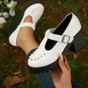 Detail van witte Mary Janes met dikke zwarte plateauzool en gouden stud details.