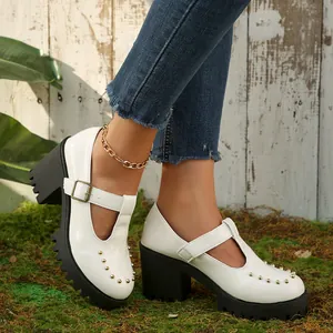 Detail van witte lakleren Mary Jane schoenen met dikke plateauzool en gouden noppen