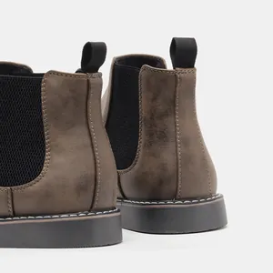 Detail view of brown Chelsea boots with black elastic side panels and sturdy pull tabs.