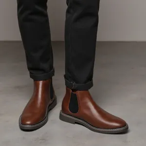 Close-up detail of men's vintage brown Chelsea boots styled with dark cuffed jeans