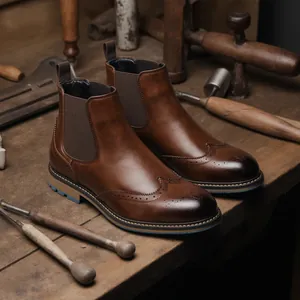 Detailansicht brauner Brogue Chelsea Boots aus Leder auf einem Werkstattisch.
