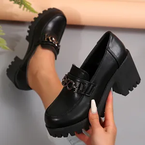 Close-up van elegante zwarte plateau loafers met een stijlvol metalen kettinggesp detail